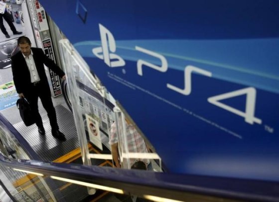 A man rides an escalator under a advertisement board of Sony Corp's PlayStation 4 game console at an electronics retailer in Tokyo