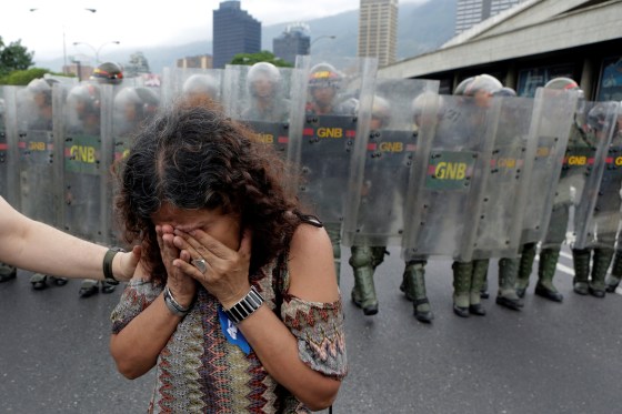 Image: An opposition supporter reacts in front of Venezuelan National Guards in a rally to demand a referendum to remove President Nicolas Maduro in Caracas