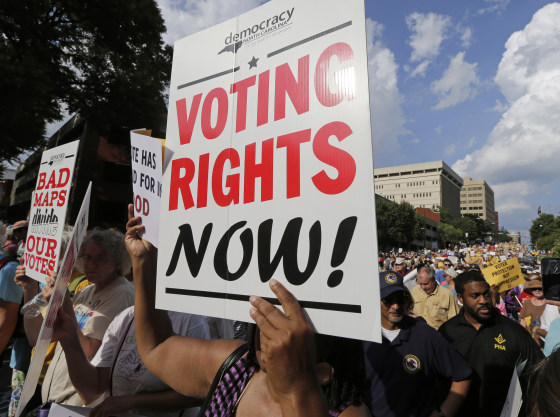 Image: A woman holds a voting rights sign as demonstrators march through the streets of Winston-Salem, N.C.