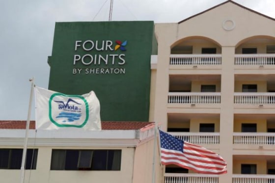 A U.S. flag and a flag of the Cuban military-run hospitality company Gaviota flutter near the logo of a \"Four Points by Sheraton\" hotel in Havana