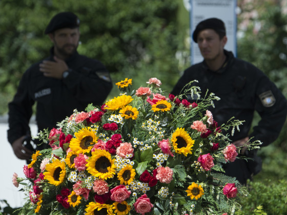 Image: Police officers stand behind a wreath near the Olympia shopping center where the shooting took place.