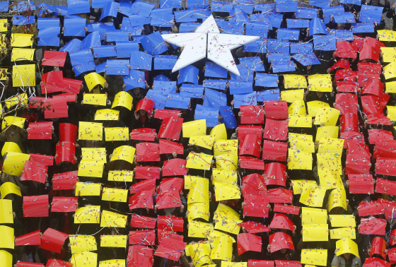 Image: People hold placards to form a giant Estelada, or Catalan separatist flag, in front of the Sant Feliu del Llobregat townhall, near Barcelona