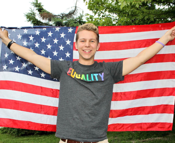 Cole Ledford holds up flag at an LGBTQ equality event in NYC (2016).