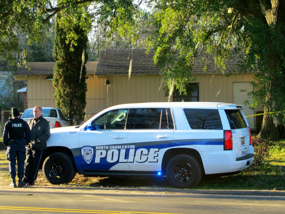 Officers stand outside a house in North Charleston, S.C., on Friday, Feb. 26, 2016, where police say a man died of an apparently self-inflicted gunshot wound after wounding a Berkeley County Sheriff's Deputy earlier in nearby Goose Creek, S.C.