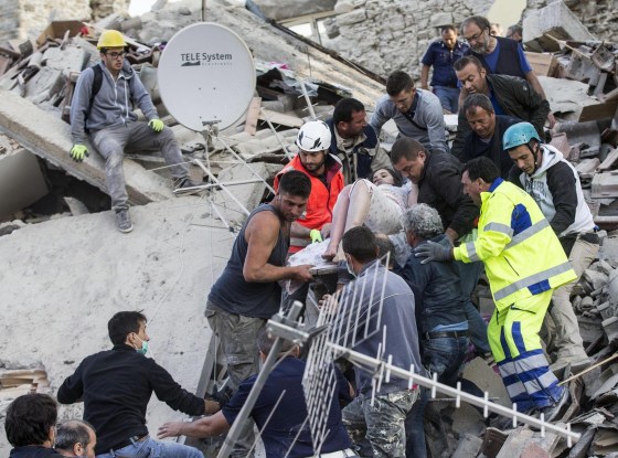 Rescuers carry an injured woman amid the rubble in Amatrice