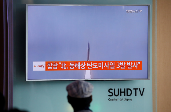 Image: A passenger watches a TV screen broadcasting a news report on North Korea firing three ballistic missiles