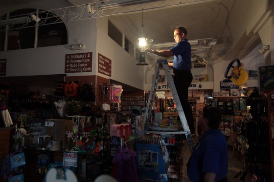 Image: The employee of a drug store hangs up a portable gas lantern during a power outage after a fire at an energy plant knocked out electricity for the bulk of the island, in San Juan