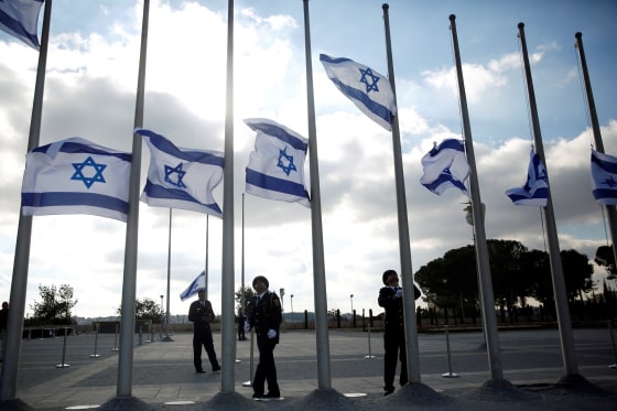 Image: Israeli presidential guards lower the national flag to half mast during a ceremony marking the death of former Israeli President Shimon Peres