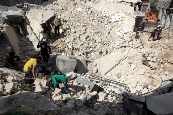 Image: First responders search a site damaged in an airstrike