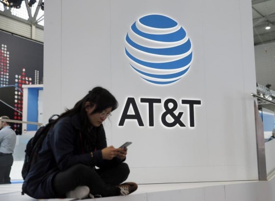 A woman looks at her mobile next to AT&T logo during the Mobile World Congress in Barcelona