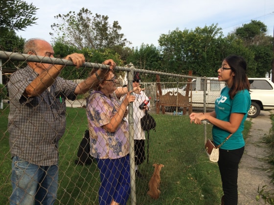 Jessica Azua, an organizer for Texas Organizing Project, speaks about voting to Lucinda Sanchez, 77 and Pablo Sanchez, 79, while their grandson Steven Sanchez, 27, stands nearby. 