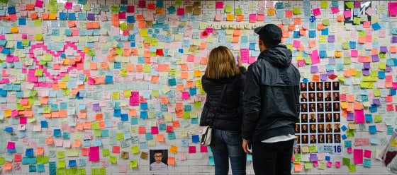 Image: People look at post-it notes covering a wall as part of the art piece 'Subway Therapy' at the Union Square subway station in Manhattan