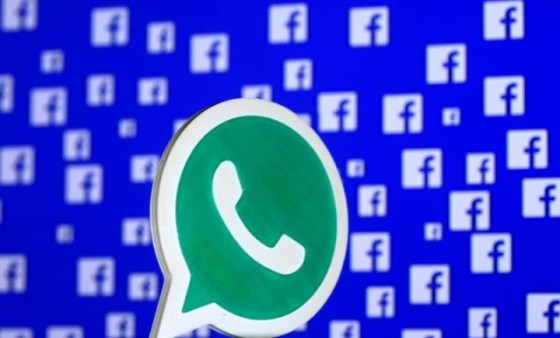 A 3D printed Whatsapp logo is seen in front of a displayed Facebook logo in this illustration taken