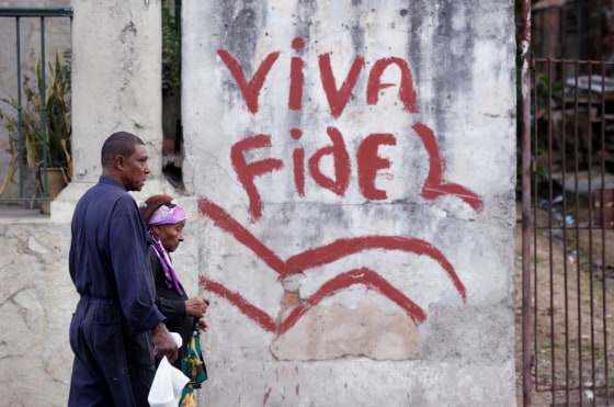Image: People walk past a graffiti that reads \"Long live Fidel\" in Havana, Cuba