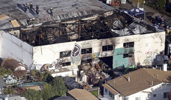 Image: Recovery teams examine the remains of the warehouse that caught fire in Oakland