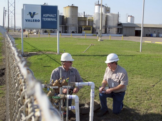 Image: Men check pipes where Corpus Christi's city-owned water main connects with an asphalt plant where a suspected chemical leak led to a city-wide ban on tap water