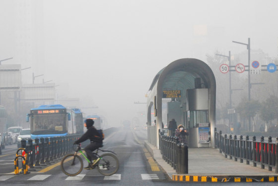 Image: A cyclist crosses a smog-shrouded street
