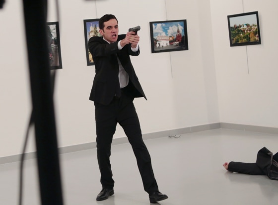 Image: An unnamed gunman gestures after shooting the Russian Ambassador to Turkey