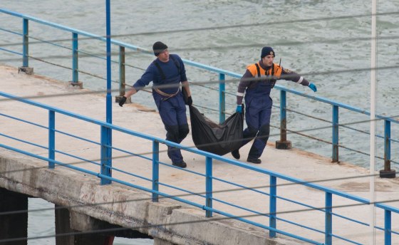 Image: Rescuers carry fragments and remains at the site of the Tu-154 plane crash near Sochi, Russia.