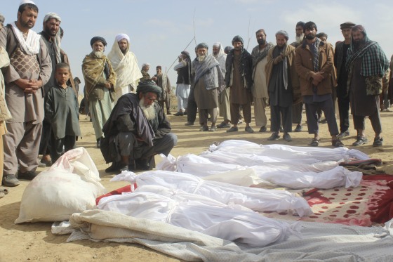 Image: Afghan villagers gather around several victims' bodies who were killed during clashes between Taliban and Afghan security forces