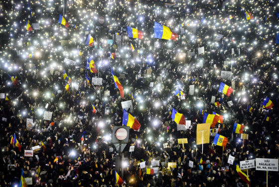 Image: Tens of thousands of people shine lights in front of the government building in Bucharest, Sunday.