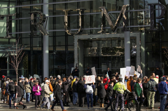 Image: Protesters hold signs outside of the Trump International Hotel and Tower during its grand opening in Vancouver