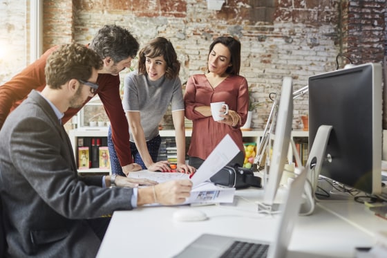 Image: Office workers gather at a desk