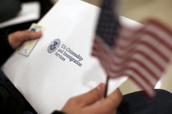 A man holds a U.S. flag while receiving his proof of U.S. citizenship during a ceremony in San Francisco
