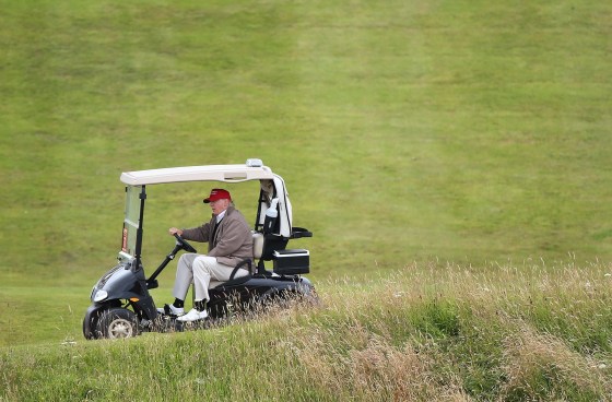 Image: Donald Trump, who says he missses driving in his new job, is seen at the wheel of a golf buggy on his resort in Turnberry, Scotland.