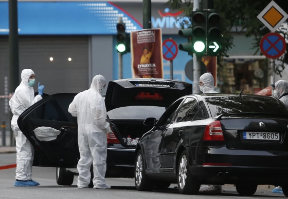 Image: Forensics officers inspect the car of former Greek prime minister and former central bank chief Lucas Papademos following the detonation of an envelope injuring him and his driver, in Athens