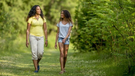 Image: A mother and daughter are walking on a grassy path through a park