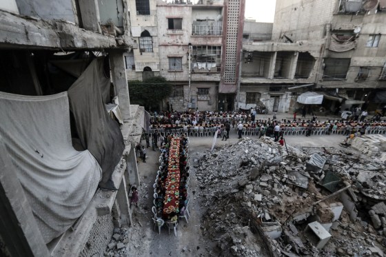 Image: People wait for Iftar, evening meal at the end of daily Ramadan fast at sunset, next to rubble and destroyed houses in Douma