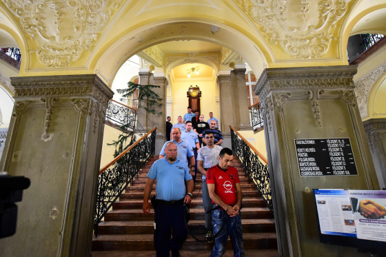 Image: Suspected smugglers are led into a Hungarian courthouse by police at the start of their trial.