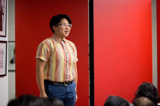 Sunshine Roc performing her story at an event featuring a book containing photos from Mia Nakano's \"Visibility Project.\"