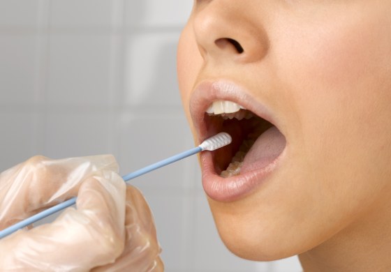 Image: A person holds a DNA swab in a woman's mouth