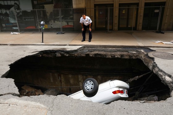 Image: St. Louis police officer looks over a large hole in 6th Street