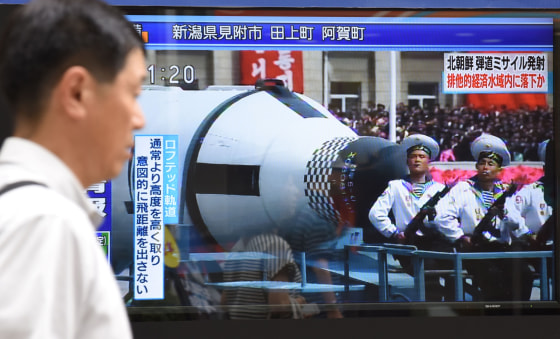 Image: A pedestrian walks past a screen broadcasting file news footage of a military parade showing North Korean soldiers and a missile, after a ballistic missile was launched by North Korea