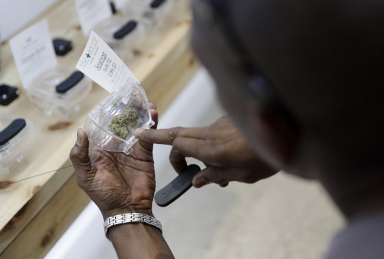 Image: A man examines marijuana for sale at The Source dispensary