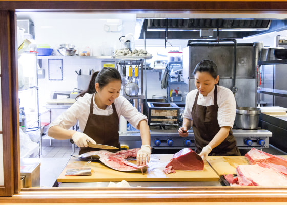 Chef Niki Nakayama (left) slices fish with sous chef and wife Carole Iida-Nakayama. At her Los Angeles restaurant, Nakayama specializes in a type of multi-course dining known as kaiseki.