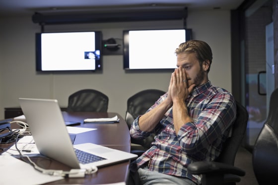 Tired businessman working at laptop in conference room