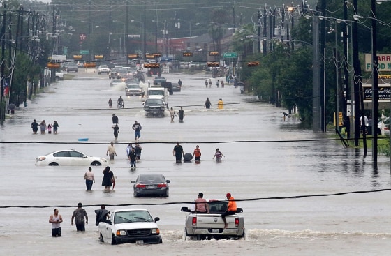 Image: People walk through the flooded waters of Telephone Rd. in Houston