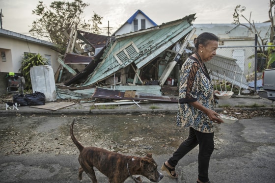 Image: Elizabeth Parilla feeds her pets in front of her damaged home, in the Santurce neighborhood of San Juan, Puerto Rico.
