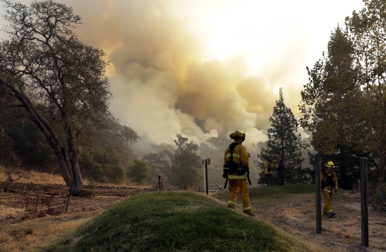Image: Firefighters walk along a containment line