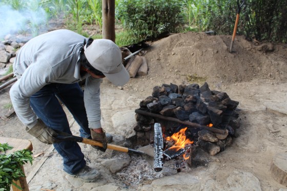 A man removes the burning firewood now that stones are hot enough for food prepared the 'pachamanca' way.