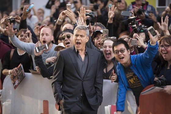 Image: George Clooney poses with fans at a film premiere