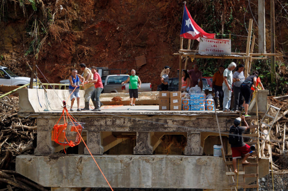Image: A group of people use a shopping cart with an improvised pulley system to transport supplies over the Vivi River