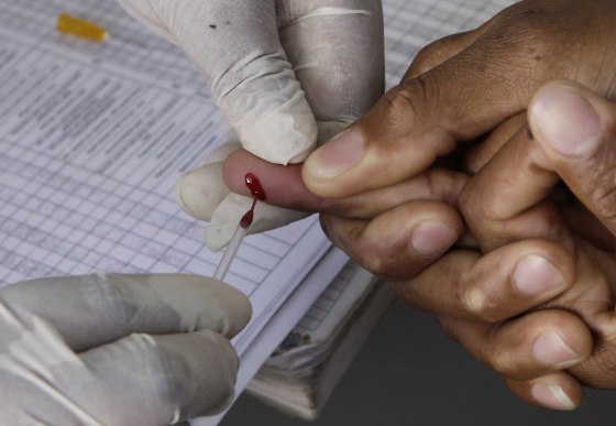 Image: A patient undergoes a pin prick blood test inside a mobile healthcare clinic