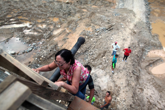 Image: People use a ladder to climb up a partially destroyed bridge after Hurricane Maria hit the area in September, in Utuado