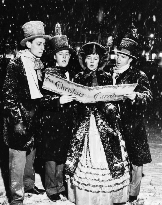 Image: Jerry Wooden, Neal Stuessi, Patricia Kidd, and Bill Piehler, dressed in 1860s style outfits sing Christmas songs