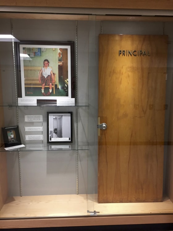 Image: A display case with photos, an illustration and the door that was once on the Principal's office at Cambridge Central Schools in Cambridge